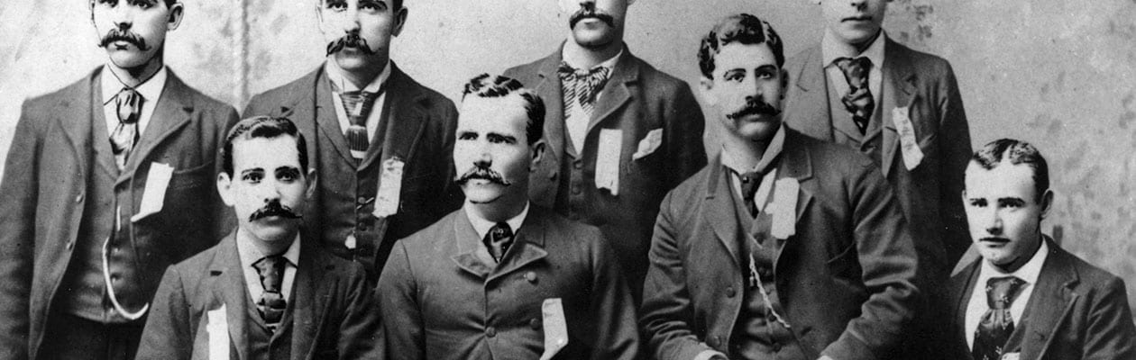 Old black and white photo of eight men in suits