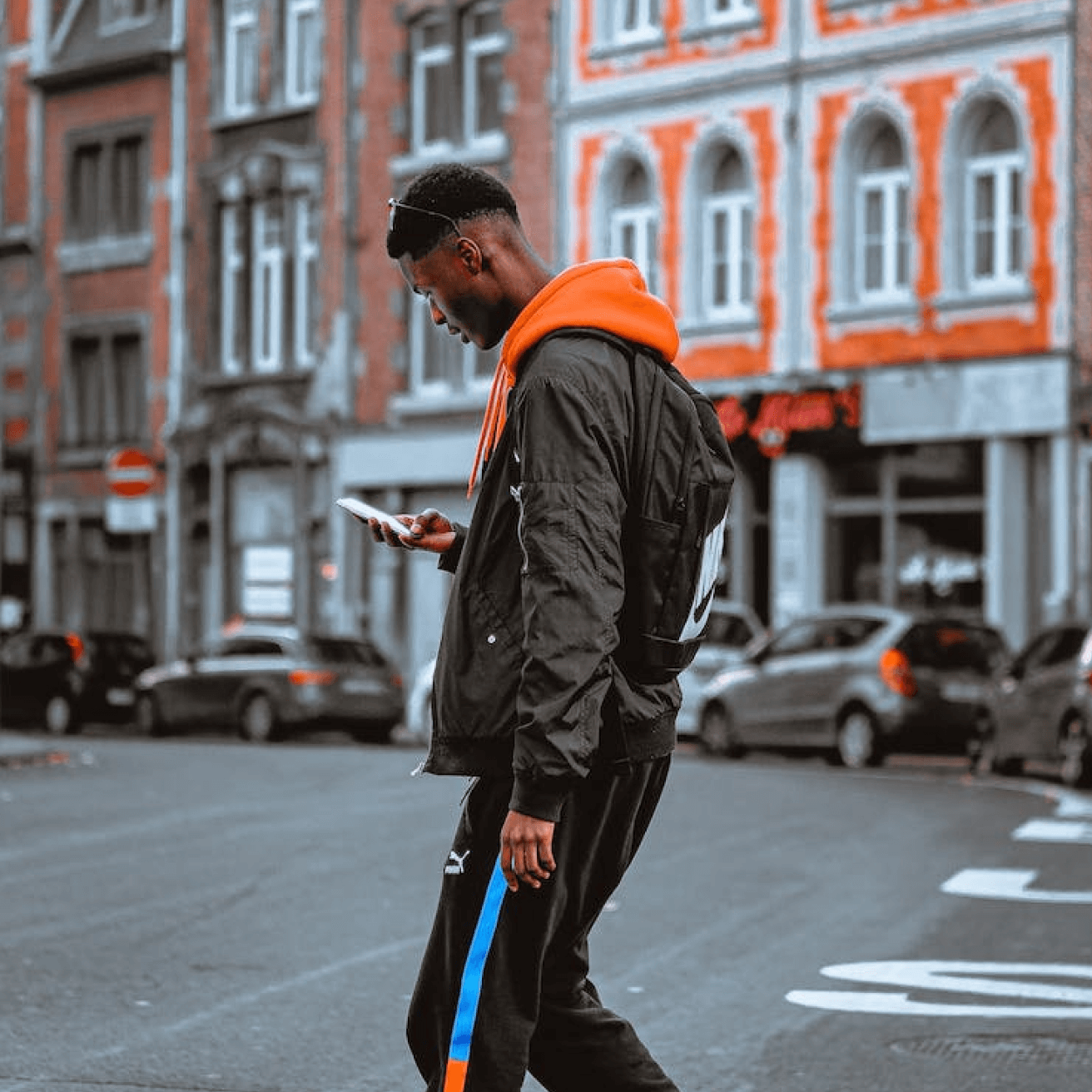 A man is walking outside looking down at his phone where he has the SimpleTexting app open.